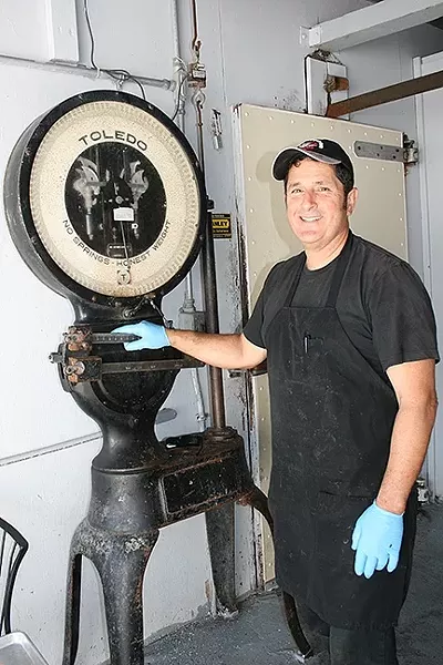 MEAT ACROSS THE AGES: Rife with history, Arroyo Grande Meat Co. has been a full-service butcher shop since 1897. This scale was used to weigh meat back in the day and—if owner/butcher Henry Gonzalez (pictured) has his way—it will one day work again. - PHOTO BY HAYLEY THOMAS CAIN