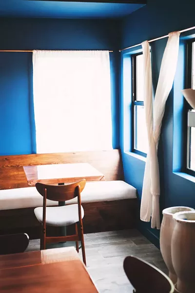 LOW TIDE, HIGH STYLE Oceanic blues mingle with wood furniture, ceramic plates, and gold flatware. - PHOTO COURTESY OF BLUE HERON