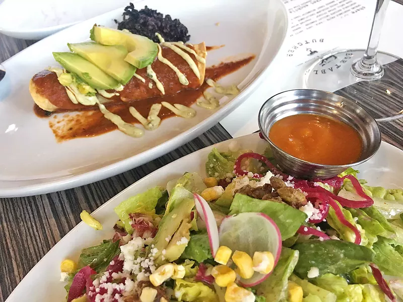 PLANT PARTY The Vegetable Butcher's market enchilada filled with kale and black beans topped with cashew crema and avocado is paired with the Little Casa salad, with little gem, raddicchio, avocado, radish, hibiscus pickled onion, queso fresco, sweet dried corn, bourbon pepitas, and cilantro vinaigrette. - PHOTO BY REID CAIN