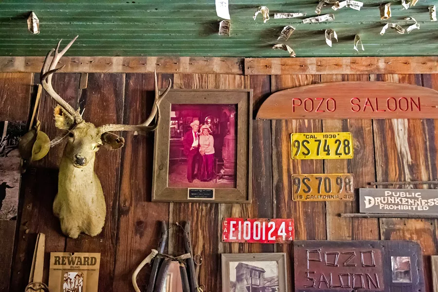 DOLLAR BILLS AND BULLET HOLES? Dozens of dollar bills have been pinned to the saloon ceiling by patrons, and some speculate that Wild West-era bullets left holes up there. - PHOTO BY JAYSON MELLOM