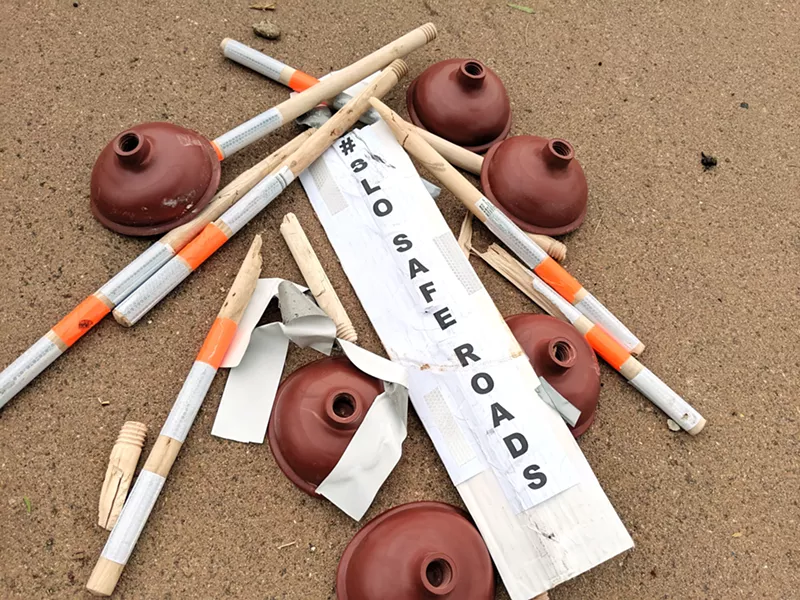 TOPPLED Demonstrators' temporary bike lane barriers lie in a pile on Aug. 28. After SLO bike advocates installed plungers as lane delineators on three busy streets, cars hit and destroyed many of them, according to participants. - COURTESY PHOTO