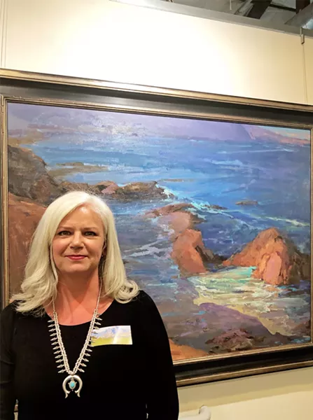 CONTEMPORARY GREATS Lori Putnam stands with her work titled Harmony Headlands. Her inspiration, Edgar Payne's Dana Point, is hung right next to Putnam's modern take. - PHOTO BY MALEA MARTIN