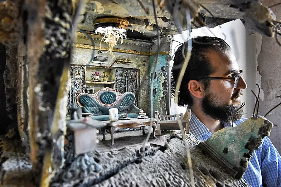 AN ARTIST AND HIS WORK Artist Mohamad Hafez is seen through one of his sculptures, which features mini-house scenes situated among found objects. - PHOTO COURTESY OF MOHAMAD HAFEZ