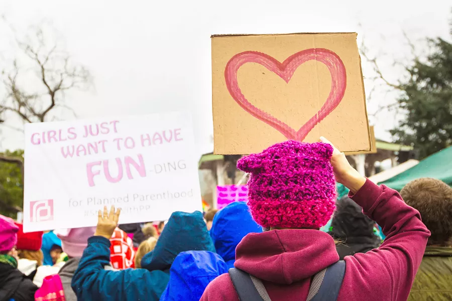 TIME IS NOW Women's March SLO attendees hold signs in Mitchell Park at the inaugural event in 2017. The fourth annual Women's March takes place on Jan. 18. - FILE PHOTO BY JAYSON MELLOM