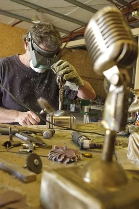 Baxter sands down one of the awards to prepare it for the patina. - PHOTO BY STEVE E. MILLER