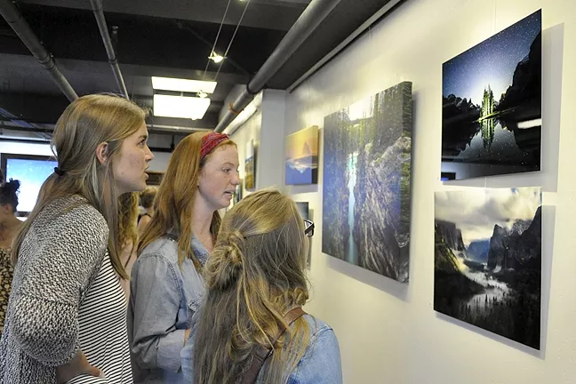 INSPIRED: Alisha Ostby, Olivia Essen, and Gigi Greene check out Burkard’s photos. Essen said before she saw his photography, she thought anyone could take a good photo. “It’s amazing, quite honestly, he’s one of the photographers that pushed me into looking deeper into photography,” she says. - PHOTO BY CAMILLIA LANHAM