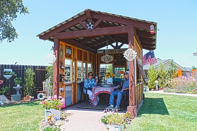 INDOORS OUTSIDE: Sandy and Virgil Clarke’s shed constructed by A Place to Grow offers the couple a break from the afternoon wind as well as a shady spot to enjoy some wine. - PHOTO BY JOE PAYNE