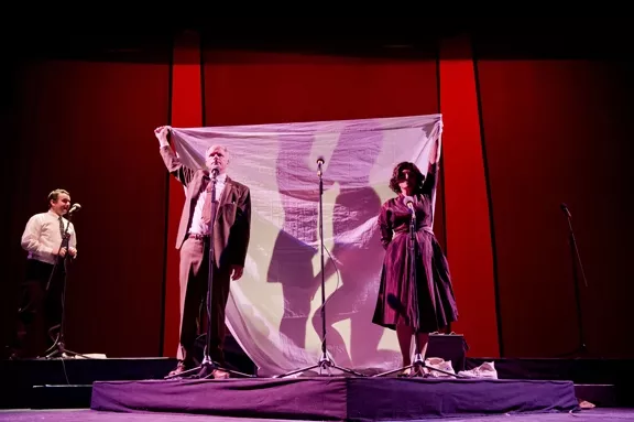 PAY NO ATTENTION TO THE SEX BEHIND THE CURTAIN!: L.A. Theatre Work’s production of The Graduate, adapted as a live radio play, incorporates visual as well as aural tricks to tell the story of Ben Braddock and Mrs. Robinson—played by Brian Tichnell and Heidi Dippold, pictured behind the bed sheet. In a simultaneous scene, Ben’s parents—played by Tom Virtue and Diane Adair—hold the sheet aloft, oblivious. Darren Richardson plays the psychiatrist in the left hand corner. - PHOTO BY MATT PETIT