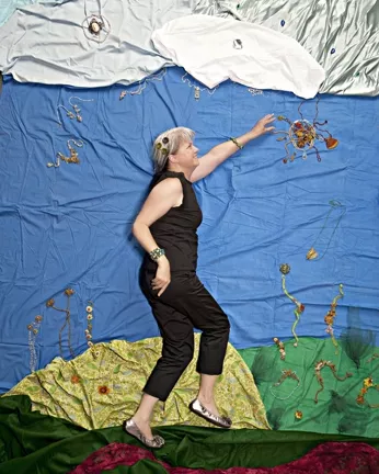 REACH FOR THE SKY : Jeweler Debra Jurey grasps the sun in a garden of her own making, in the first of four experimental New Times Autumn Arts photo shoots. - PHOTO BY STEVE E. MILLER