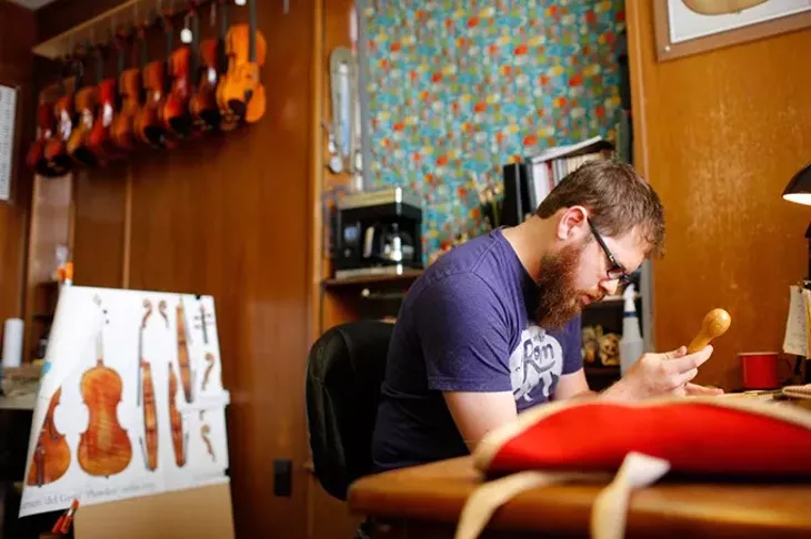 Arsenios Corbishley works on a violin at the Paramount Building in Oklahoma City, Tuesday, Oct. 6, 2015. - GARETT FISBECK