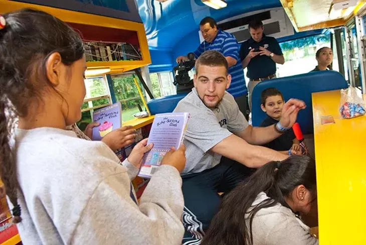 Rookie Thunder forward, Mitch McGary, helps Putnam Heights Elementary students pick out books inside the Rolling Thunder Book Bus, 9-11-2014. mh