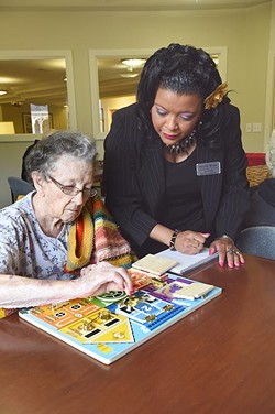 Aquilla Butler, activities coordinator at Prairy Winds Alzheimer's Special Care Center, helps a resident work a puzzle as part of Alzheimer's therapy daily rituals.  mh