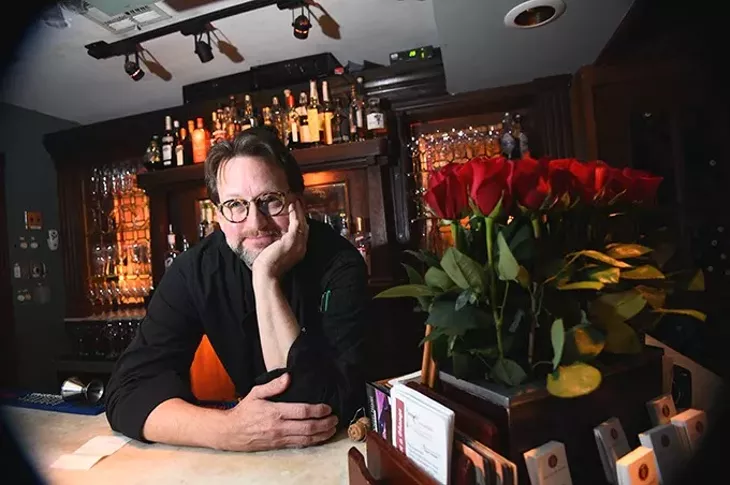 Kurt Fleischfresser takes poses with roses at his position at the reception desk at The Coach House in Nichols Hills, 1-25-16. - MARK HANCOCK