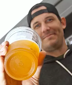 Josh Sylvester, bartender and everything else at The Bleu Garten, displays a recycle symbol on the bottem of one of its draft beer cups. (Mark Hancock)