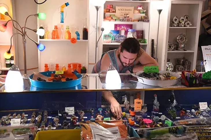 Brandon Martin, store manager, arranges glass pipes, at The Indigo Attic in Oklahoma City, 11-11-15. - MARK HANCOCK