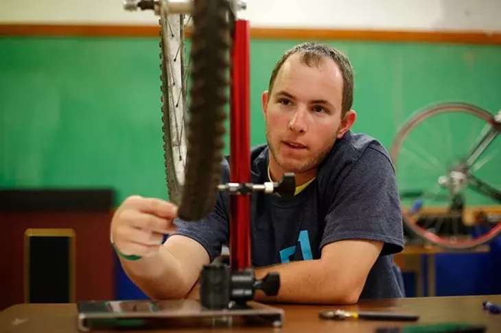 Brendan Heitz, a mentor from the University of Oklahoma, helps true a bicycle wheel at Emerson High School in Oklahoma City, Wednesday, May 6, 2015. - GARETT FISBECK