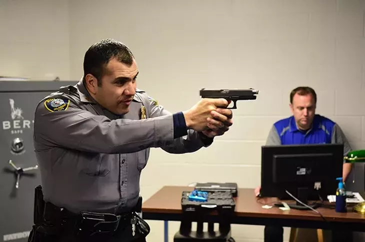 Captain Paco Balderrama fires of a few rounds during a police training simulation using CO2 cartriges and electronics, with Sargent Shawn Byrne controlling the scenario from a computer in background. mh