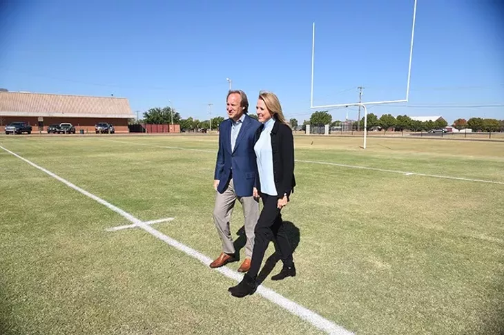Tim and Liz McLaughlin helped start the Fields and Futures Foundation, shown walking a new football field constructed at Webster Middle School, 10-14-15. - MARK HANCOCK