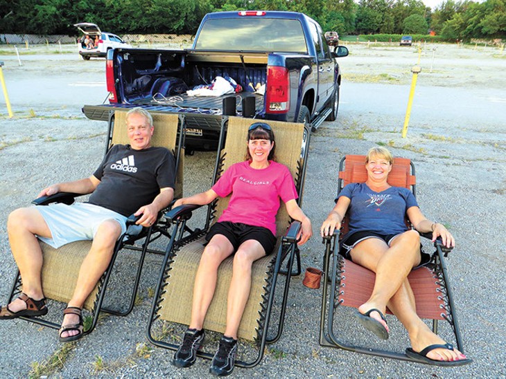 Lloyd and Charlotte Kutch (left and middle) and Brenda Bischoff join other early arrivers as they prepare for the first of two first-run movies. Lloyd wired in jacks to the back of his truck to plug in speakers especially for their visits to the Winchester. - BRETT DICKERSON