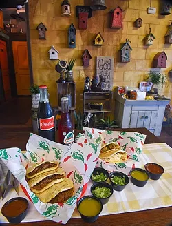 An assortment of pork crackling, chicken with cream, and beef barbacoa gorditas, with sauces and beverages if front of a homey, bird house and crafts wall at Gorditas Mexican Kitchen, 11-2-15. - MARK HANCOCK