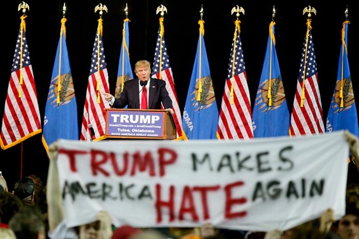 Republican Presidential candidate Donald Trump addresses a crowd while protestors hold up a sign during his rally at the Mabee Center at Oral Roberts University in Tulsa, Jan. 20, 2016. (Photo Ian Maule / Tulsa World / File / Provided)