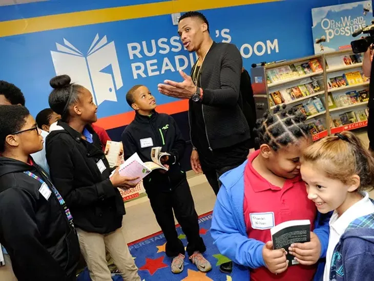 Russell Westbrook helps students pick out books during a book fair and opening of Russell's Reading Room at Edwards Elementary School in Oklahoma City, Tuesday, Jan. 5, 2016. - GARETT FISBECK