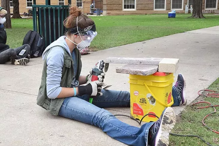 Art student Alice Dunaway forms granite pieces with an angle grinder as part of the Coming Together Park sculpture being installed on the USAO campus. mh