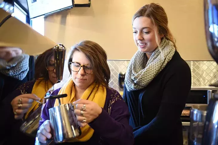 From left, Alissa Williams steams milk in a coffee drink preparation while shop owner Ally Moore watches, at Compass Coffee Shop in Edmond. mh