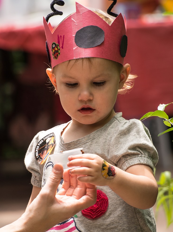 A child enjoys viewing a ladybug while dressed as a ladybug. - Photo by Carl Shortt - CARL SHORTT