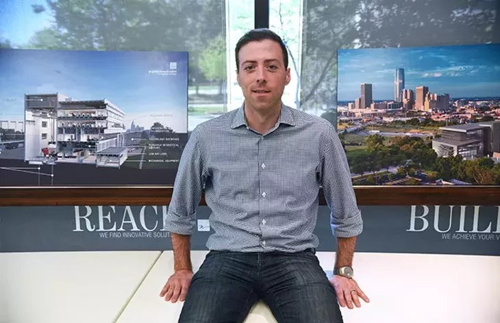 Cory Baitz, an architect with Miles Associates and is also on Oklahoma City's Downtown Design Review Committee, poses with artist renderings of the G.E. Global Research Center now under construction accross the street from his office. mh