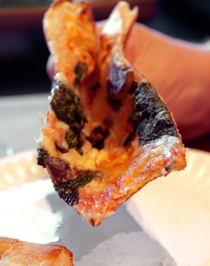 A customer folds his big floppy slice of Fungus Among Us for eating, at Empire Slice House. (Mark Hancock)