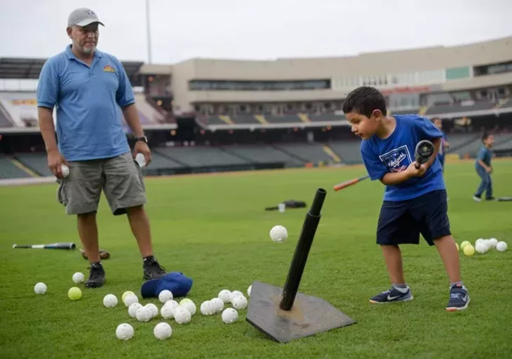 Emiliano Hernandez, 6, hits a ball off a tee as his father, Jorge, looks on during an OKC Dodgers Clinic in conjunction with Supermercados Morelos, Friday, July 28, 2017. - GARETT FISBECK