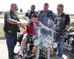 Members of the Survivors Clean and Sober Motorcycle Club give McCarty Center patient Xaviar Smith a taste of what riding a Harley is like during last year’s Ride for Recovery. The Ride for Recovery poker run benefits Camp ClapHans, a summer camp program of the J. D. McCarty Center. - PHOTO BY SHARLA BARDIN