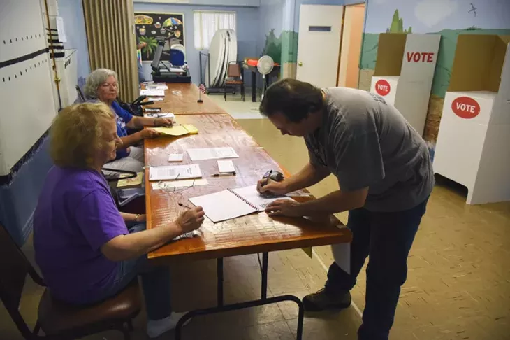 John Harrison signs in with election officals, from left, Eva Welch and Mary Austin, during the election on 7-14-15, at Crown Heights Church of the Nazarene. mh
