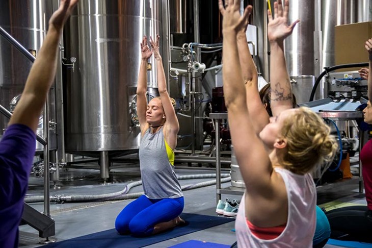 Surrounded by brewing equipment, Instructor Brooke Larson leads a class of Beer Yoga, at Coop Ale Works in southwest Oklahoma City, 10-15-2016. - MARK HANCOCK