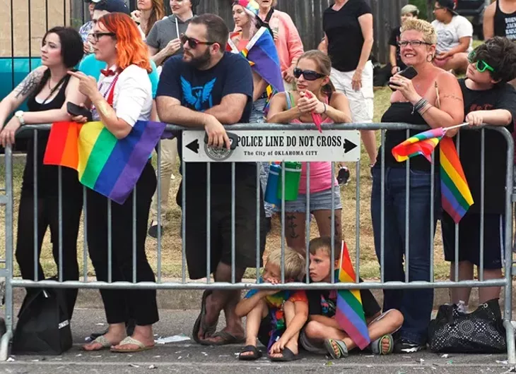 Two young boys sit on the ground watching the Pride Parade on Sunday, June 25, 2017. (Cara Johnson).