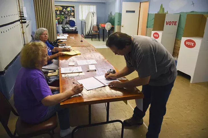 John Harrison signs in with election officals, from left, Eva Welch and Mary Austin, during the election on 7-14-15, at Crown Heights Church of the Nazarene. mh