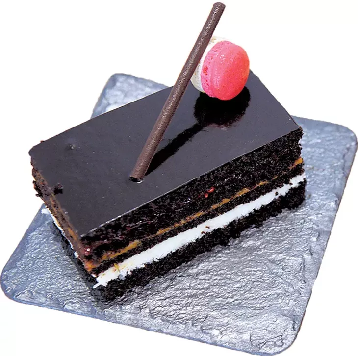 An opera cake with layers of raspberry, dulce de leche and white chocolate is joined by below a variety of ganache-filled macarons. - JACOB THREADGILL