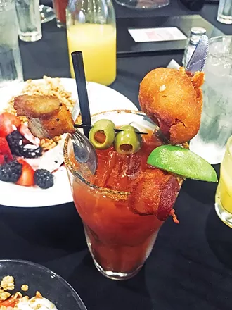 A bloody mary topped with a housemade corn dog, bacon and pork belly - JACOB THREADGILL