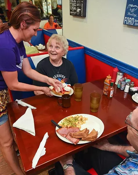 Waitress Renee Wilson serves regulars Virgie and Bob Cherry hearty breakfast dishes, Stawberry Waffle with Whipp Cream and a 8oz Ham with Eggs, Homefries and Wheat Toast, at the All American Diner in Midwest City, 9-18-15. - MARK HANCOCK
