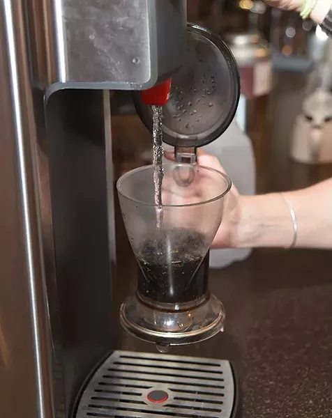 Kristy Jennings pours hot water into the black currant tea leaves during the iced tea making process. mh