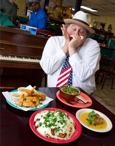 Chicago Dan plays the harmonica at Cajun King regularly. In frony of him sits, fried catfish, etoufe, spicy chicken pasta, and bread pudding. (Shannon Cornman)