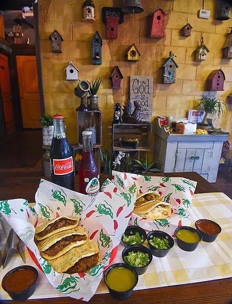 An assortment of pork crackling, chicken with cream, and beef barbacoa gorditas, with sauces and beverages if front of a homey, bird house and crafts wall at Gorditas Mexican Kitchen, 11-2-15. - MARK HANCOCK