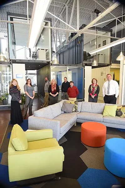 Employees of the Oklahoma Public School Resource Center pose inside with shipping container constructed offices and modern decor. mh