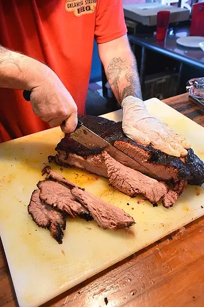 Brian Keefe slices brisket as he would for someone ordering for a Football Watch Party, at Oklahoma Station BBQ. mh