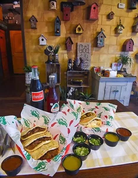 An assortment of pork crackling, chicken with cream, and beef barbacoa gorditas, with sauces and beverages if front of a homey, bird house and crafts wall at Gorditas Mexican Kitchen, 11-2-15. - MARK HANCOCK