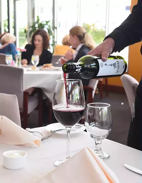 Waitress Elizabeth Wilson pours LA Capra Pinotage wine at the Museum Cafe recently. mh