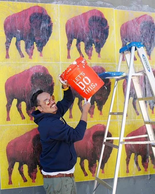 Steven Paul Judd uses wheat paste as he creates a mural on an outside wall of Stash in Norman. - GARETT FISBECK