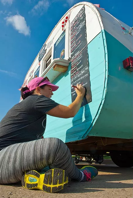 Writing up the menu on Katiebug's Shaved Ice before things get busy outside the grand opening of Sweets & Spurs new location, during a parking lot celebration at Casady Square on 10-23-14. mh