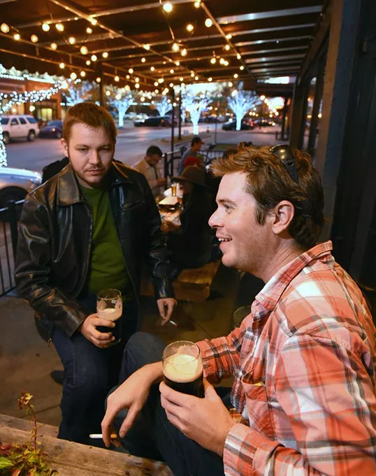 John Lepak and Cody Jennings enjoy Guiness drafts and smokes, on the pateo at Saints in the Plaza District, OKC, 11-25-15. - MARK HANCOCK
